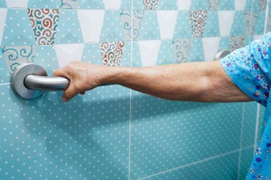 Asyalı yaşlı kadın banyoda güvenlik korkuluğu kullanıyor..