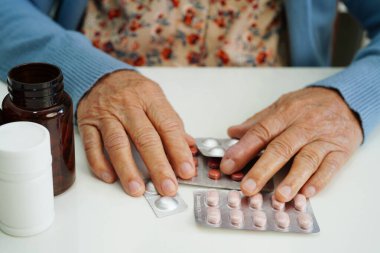 Asyalı yaşlı kadın bardakta suyla birlikte hap tutuyor. Sağlıklı, güçlü bir ilaç..