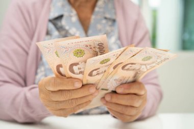 Retired elderly woman counting coins money and worry about monthly expenses and treatment fee payment.