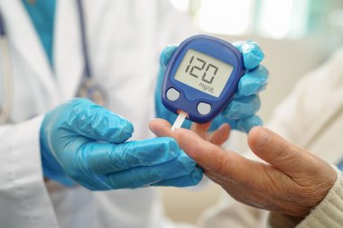 Diyabet tedavisinde kan şekeri seviyesini kontrol etmek için dijital glikoz ölçer kullanan Asyalı doktor.