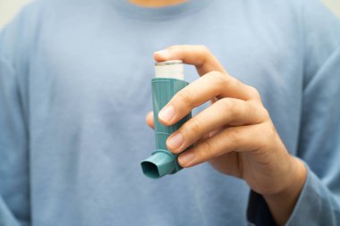 Astım ve kronik obstrüktif akciğer hastalığı COPD, Asyalı genç adam ölçülü doz solunum cihazı kullanıyor..