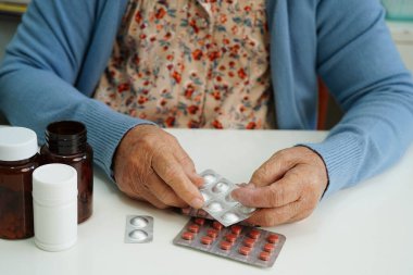 Asyalı yaşlı kadın bardakta suyla birlikte hap tutuyor. Sağlıklı, güçlü bir ilaç..