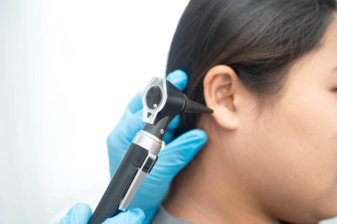 Otolaryngologist ya da ENT hekim doktoru yaşlı hasta kulağını otoskopla muayene ediyor, işitme sorunu var..