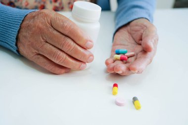 Asyalı yaşlı kadın bardakta suyla birlikte hap tutuyor. Sağlıklı, güçlü bir ilaç..