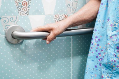 Asyalı yaşlı kadın banyoda güvenlik korkuluğu kullanıyor..