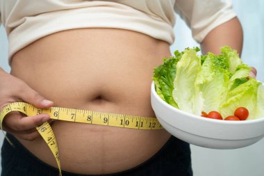 Koca göbekli, şişman, kilolu ve sağlıklı yiyecekleri olan Asyalı bir kadın..