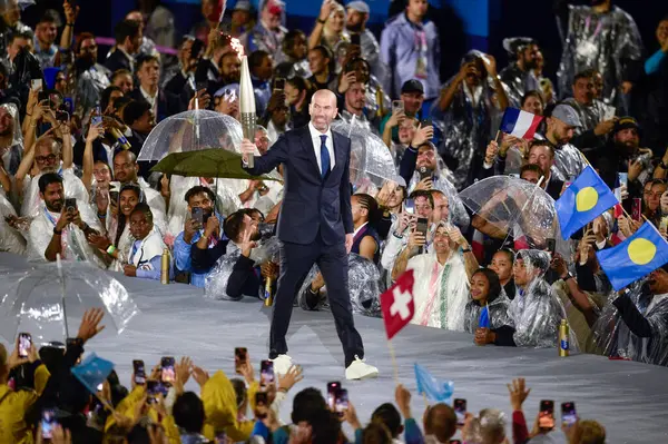 PARIS, FRANCE-26 Temmuz 2024: Eski futbolcu Zinedine Zidane, Paris 2024 Olimpiyat Oyunlarının açılış töreninde meşaleyi taşıdı