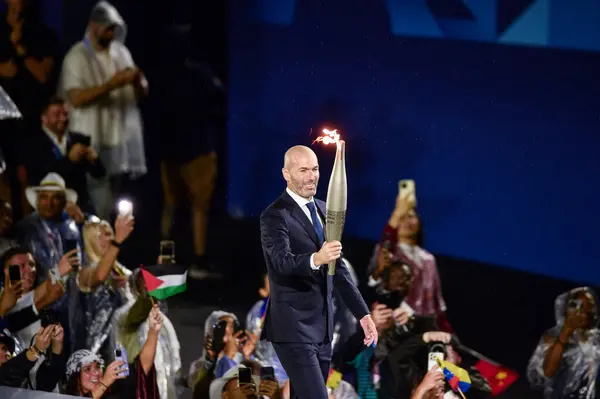 PARIS, FRANCE-26 Temmuz 2024: Eski futbolcu Zinedine Zidane, Paris 2024 Olimpiyat Oyunlarının açılış töreninde meşaleyi taşıdı