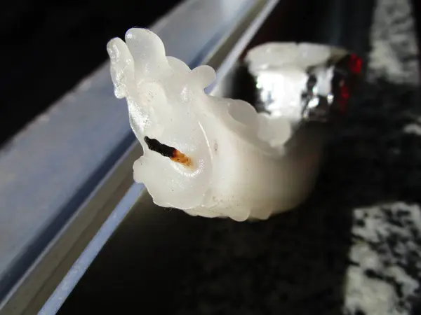 Isı tarafından söndürülmüş ve bükülmüş beyaz bir mumun yakın plan çekimi.