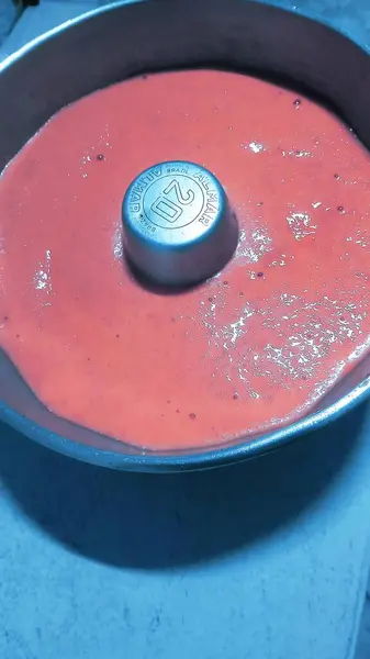 Ortasında pipo olan bir kek tepsisi ve masada çiğ kirazlı kek hamuru.