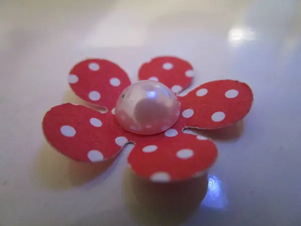 Kırmızı ve beyaz çiçekli süs, ortasında detaylar var.