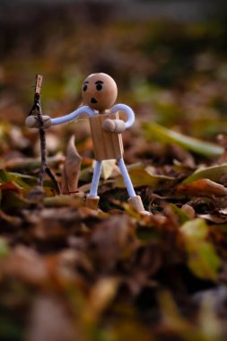 Ahşap figür, elinde bir sopayla düşen sonbahar yapraklarının arasında yürüyüş yapıyor. Yürüyen bir sopa gibi davranıyor.