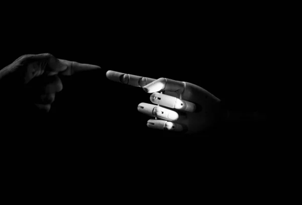hands bumping finger in the dark with black background one wooden hand another human creative photography
