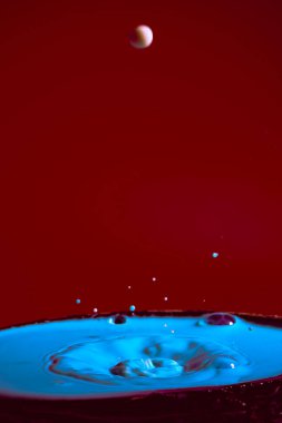 Mor bir zemin üzerinde mavi rengin hareket eden su damlalarının çarpışması düşerken ve birbirleriyle çarpıştığında şekiller ve dalgalar oluşur. Fotoğraf ve yüksek çözünürlüklü görüntüler gevşeme fotoğrafçılığı