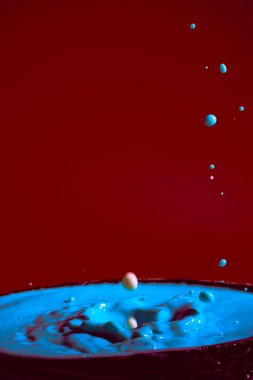 Mor bir zemin üzerinde mavi rengin hareket eden su damlalarının çarpışması düşerken ve birbirleriyle çarpıştığında şekiller ve dalgalar oluşur. Fotoğraf ve yüksek çözünürlüklü görüntüler gevşeme fotoğrafçılığı