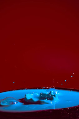 Mor bir zemin üzerinde mavi rengin hareket eden su damlalarının çarpışması düşerken ve birbirleriyle çarpıştığında şekiller ve dalgalar oluşur. Fotoğraf ve yüksek çözünürlüklü görüntüler gevşeme fotoğrafçılığı