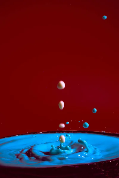 stock image collision of moving water drops of blue color on a purple red background forming figures and waves when falling and colliding with each other photography and high resolution images relaxation photography