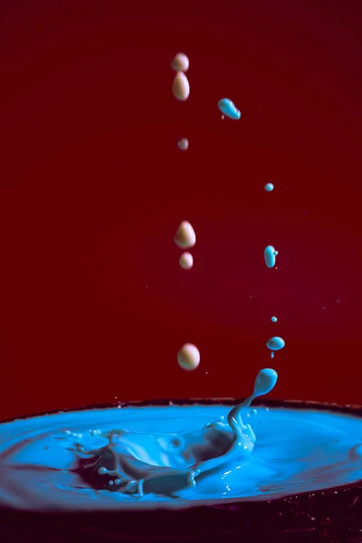 Stock image collision of moving water drops of blue color on a purple red background forming figures and waves when falling and colliding with each other photography and high resolution images relaxation photography