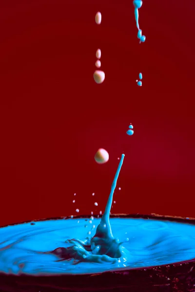 stock image collision of moving water drops of blue color on a purple red background forming figures and waves when falling and colliding with each other photography and high resolution images relaxation photography