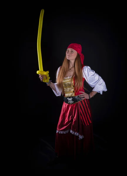 woman with long hair dressed as a pirate in a red suit and with a yellow balloon in the shape of a sword in her hand photography of party events