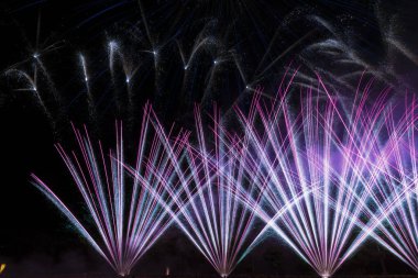 Yeni yıl şenlikleri, yeni yıl arifesi. Karanlık gökyüzündeki havai fişeklerin renkleri, göl ışığı şenliklerinin suyuna yansıyan renkli roketler.