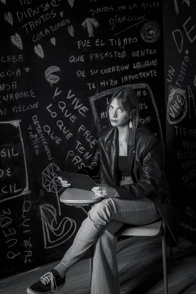 ノートパソコンを持った大学の椅子に座っている美しい若い女性の白黒のイメージです — ストック写真