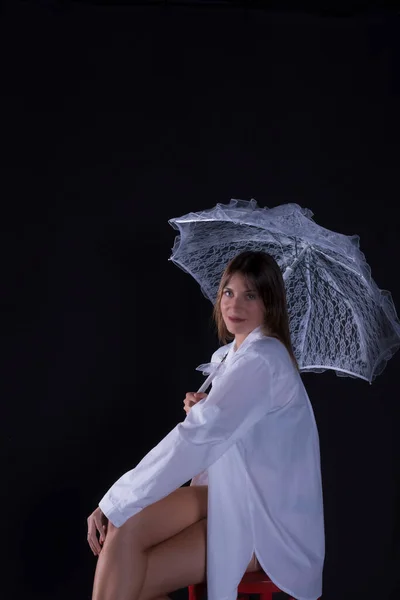 美しい女性の黒い背景に白い傘を差した白いシャツを着た美しい若い女性 — ストック写真