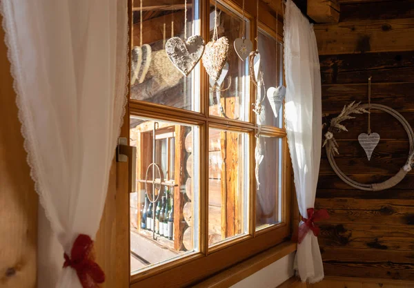 Mountain hut window with white curtains and Christmas decorations on a clear winter day, Austria, Salzburg. High quality photo