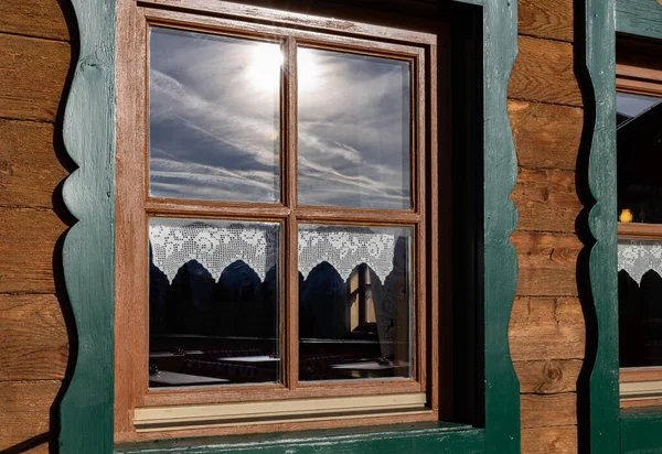 Mountain hut window reflecting dramatic cloudy sky, Austria. High quality photo