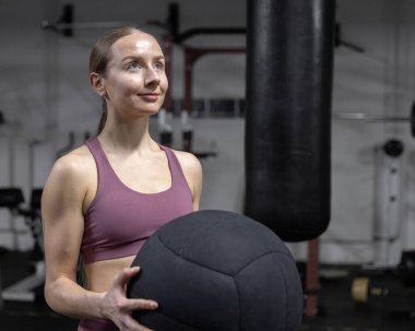 Long-haired, graceful boxer girl trains with a heavy ball in the gym. High quality photo