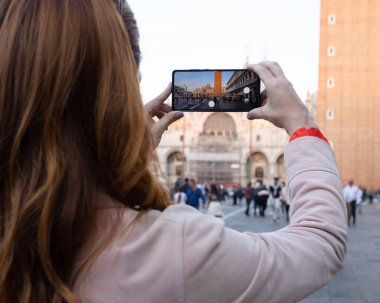 Genç bir kadın tarihi bir yerde telefonuyla resim çekiyor. İtalya, Venedik. Yüksek kalite fotoğraf