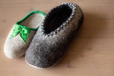Ahşap bir zeminde kurumuş yün tezgahtan yapılmış çiftsiz erkek ve kadınların ev ayakkabıları. Yüksek kalite fotoğraf