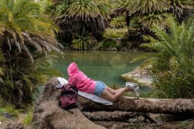 O genç kadın, bir hurma ağacının kütüğünün kütüğüne yaslanmış, o ağacın meyvesinden sarkan bir kitap ve hurma dalları imiş. Yüksek kalite fotoğraf