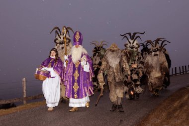 Noel alayı Aziz Niklas ve Krampus kırsal bir yolda, alacakaranlıkta karın altında, Avusturya, Gastein. Yüksek kalite fotoğraf