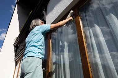 Sokak tarafından ev pencerelerini temizleyen yetişkin bir adamın portresi. Yüksek kalite fotoğraf