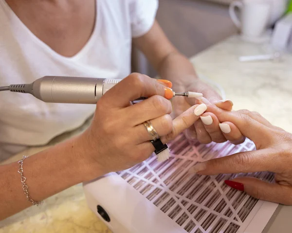 The nail technician prepares the clients nails for coating with a long-lasting gel. High quality photo
