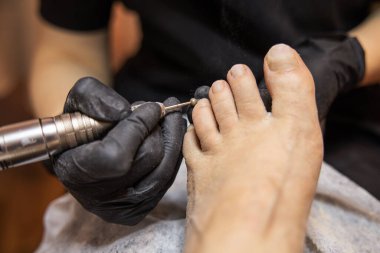 Pedikür ustası çivinin yüzeyini özel bir aletle öğütüyor. Yüksek kalite fotoğraf