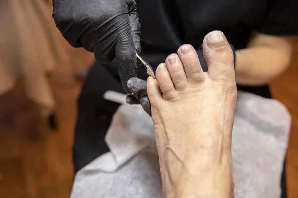 The pedicure master cuts off the nail on the little finger of the clients left foot with pinches. High quality photo