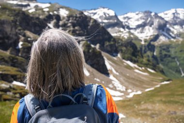 Gri saçlı, uzun saçlı bir adam yüksekte duruyor ve Avusturya 'nın karlı dağlarına bakıyor. Yüksek kalite fotoğraf