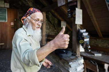 Mağaranın yaşlı bekçisi girişte duruyor ve onaylamak için parmağını kaldırıyor. Yüksek kalite fotoğraf