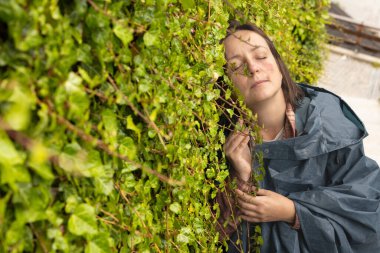 Yüzünde leke olan genç bir kadın yeşil bir duvara yaslanmış duruyor. Yüksek kalite fotoğraf