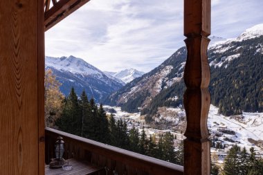 Karlı dağlardaki bir otel odasının ahşap balkonundan panoramik manzara ve bulutlu gökyüzü, Avusturya. Yüksek kalite fotoğraf