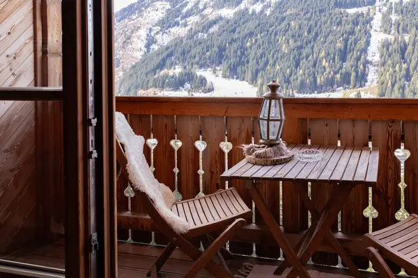 Cozy wooden balcony of the hotel room with folding furniture, mountain view with ski lift,. High quality photo