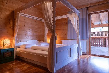 Çift kişilik yataklı ve tepe örtülü, Avusturya tarzı bir otel odasındaki yatak odasının genel planı. Yüksek kalite fotoğraf