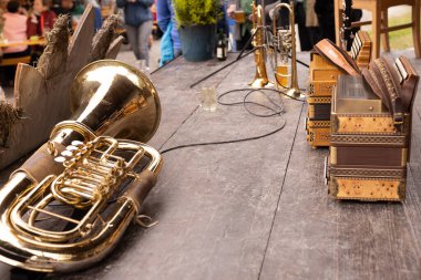 Bir altın öfonyum, bir trompet ve ahşap bir masada oturan iki akordeonun yakın plan çekimi. Enstrümanlar sıraya dizildi.