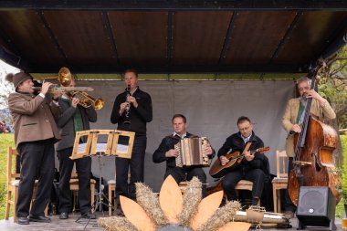 Gündelik giysiler giymiş beş müzisyenden oluşan bir grup, küçük ve kapalı bir sahnede sahne alıyor. Grup, trombon, klarnet, akordeon ve bas gibi çeşitli enstrümanlar çalıyor.
