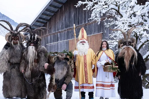 Bu resim bir grup Avusturyalı Krampus ve Aziz Nicholas karakterini karlı kış ortamında gösteriyor. Krampus kürk giymiş ve boynuzları ve maskeleri var..