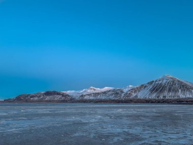 Frozen fjord Borgarfjordur near Borgarnes with some beautiful sunset lit snow covered mountains in Iceland clipart
