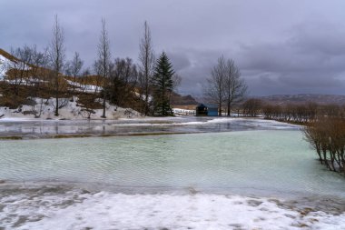 Stjornarfoss şelalesinin yanında küçük renkli kısmen donmuş bir göl. Kirkjubaejarklaustur, İzlanda 'nın yanında piknik yapmak için harika bir yer.