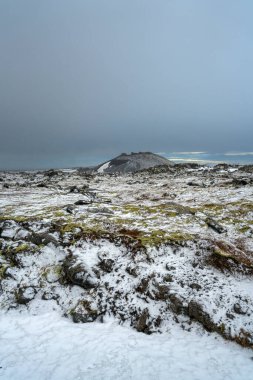 Kar Saxholl Krateri 'ni kapladı. Gri gökyüzü altında yosun kaplı lav tarlaları, Snaefellsnes yarımadası, İzlanda